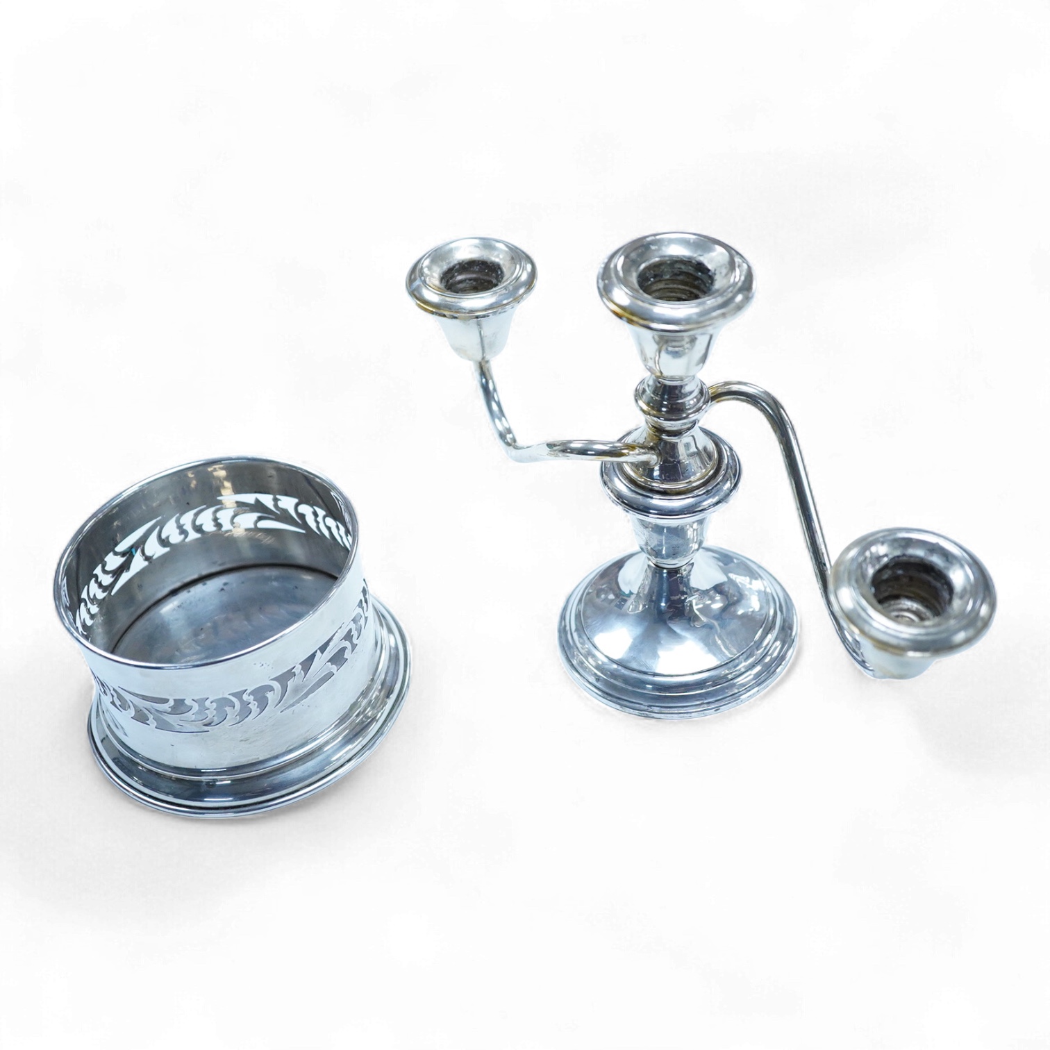 A North America sterling two branch, three branch candelabrum, by Frank M. Whiting & Co, height 15.4cm, weighted, together with a pierced 900 standard white metal bottle coaster, 5.4oz.